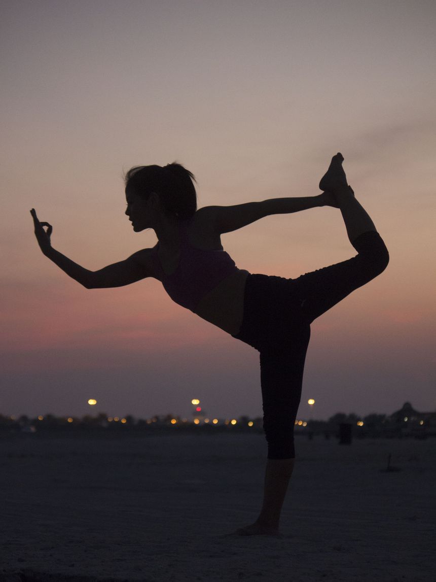 Anne Tana in der Tänzer-Haltung (Natarajasana) als Silhouette vor rosa-orangem Abendhimmel